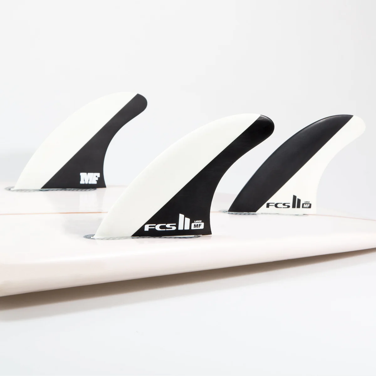 FCS II Mick Fanning Signature Black/White Tri Fins mounted on a surfboard